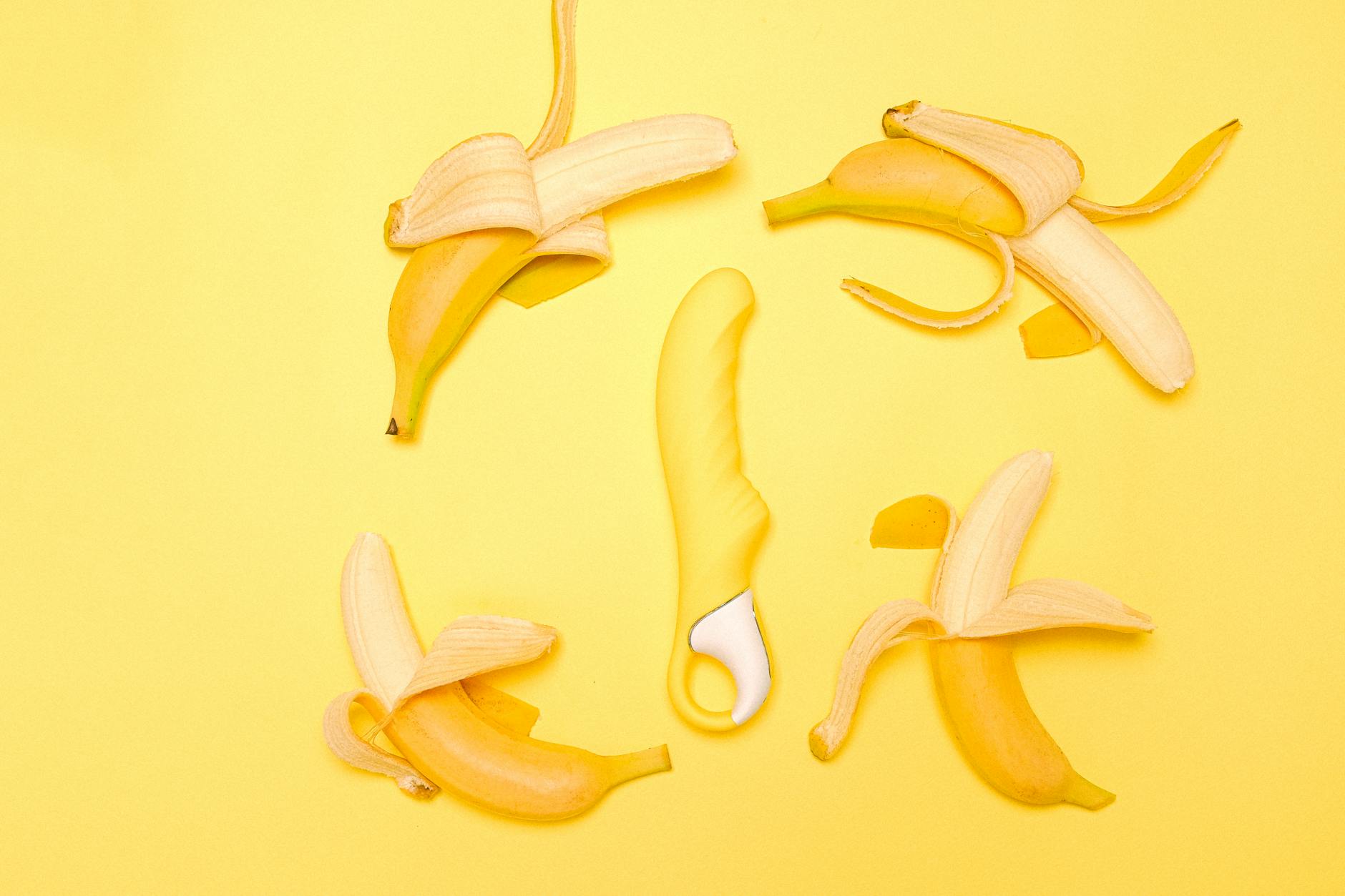 Vibratore al limone circondato da banane gialle su sfondo giallo luminoso