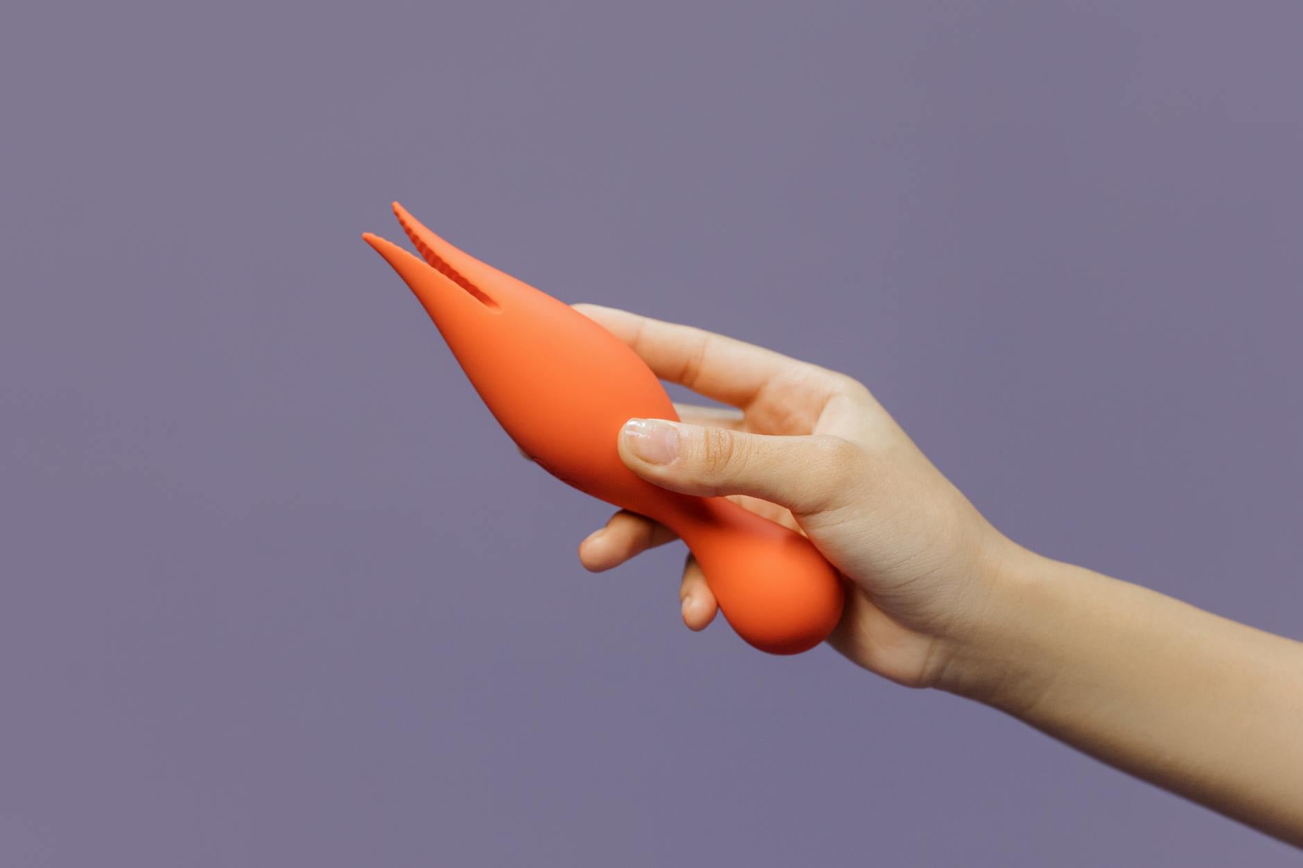 Hand holding a lemon-colored clitoral vibrator against a minimalist purple background, symbolizing gentle sensuality after burnout.