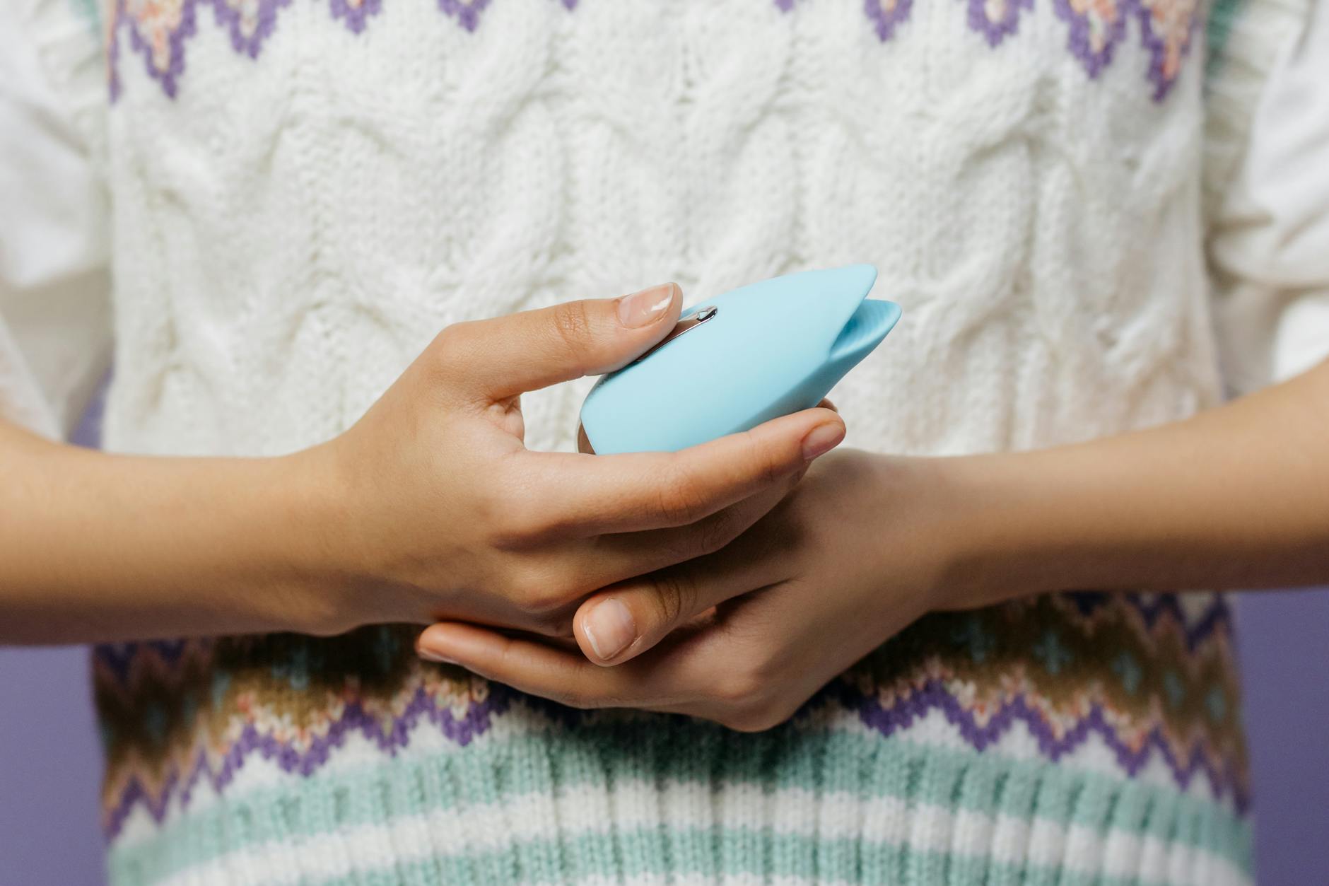 A blue silicone sex toy held in hand against a solid purple background, symbolizing self-care and pleasure recovery